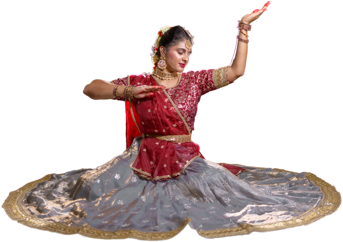 Jia seated in a Kathak posture, one hand raised, her lehenga fanned wide across the floor